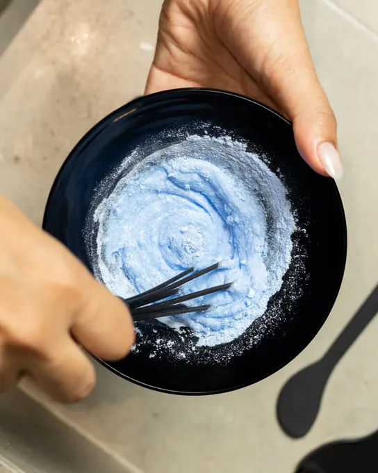 Bol noir de poudre décolorante bleue et pinceau