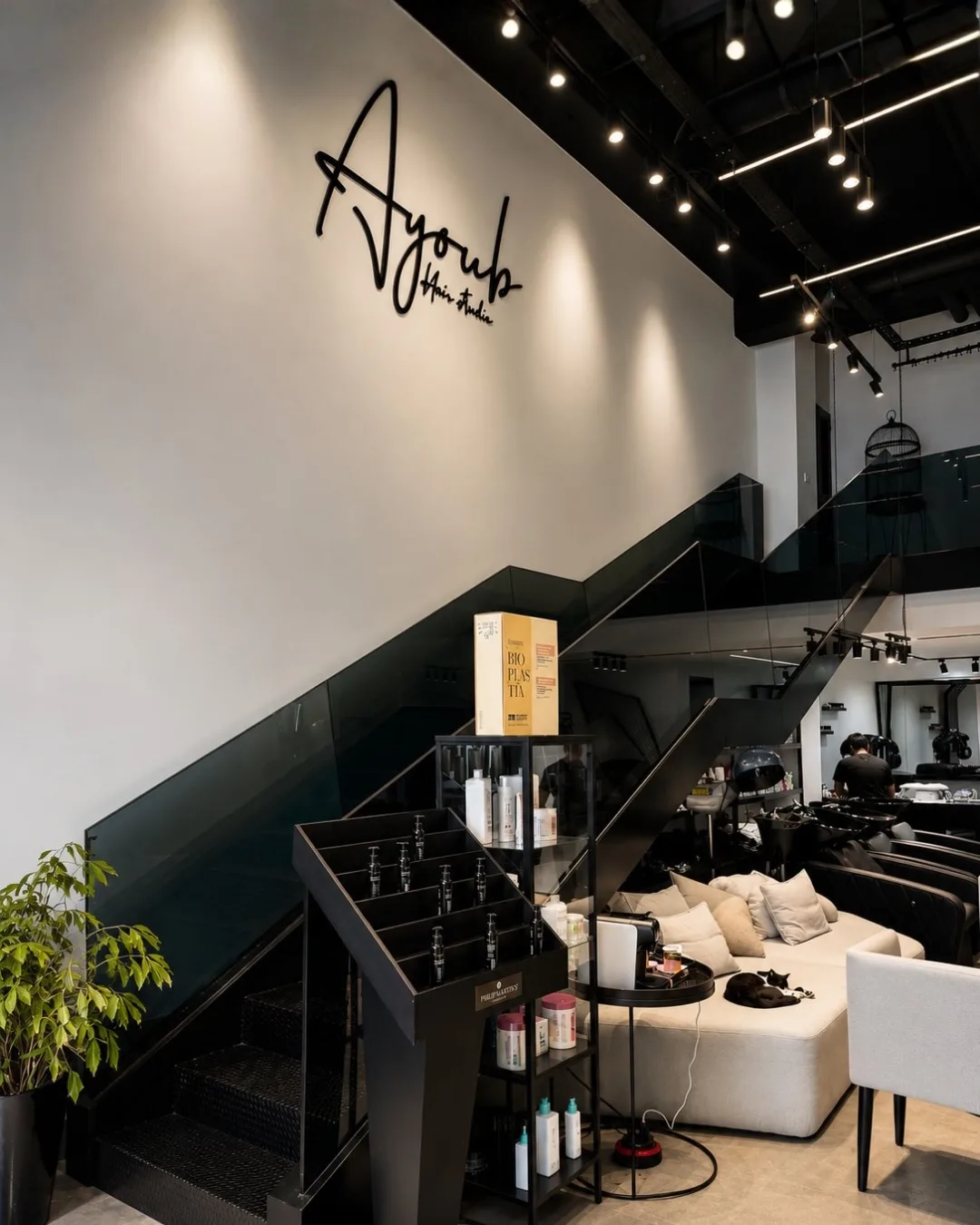 L'enseigne Ayoub Hair Studio en lettres noires sur le mur blanc du salon, sous les spots